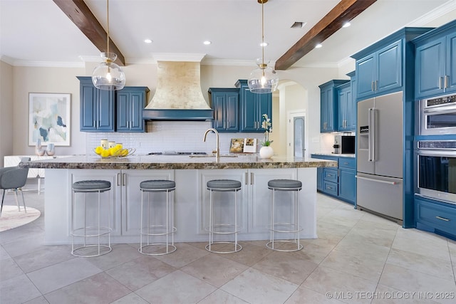 kitchen featuring blue cabinets, stainless steel appliances, a breakfast bar, hanging light fixtures, and custom range hood