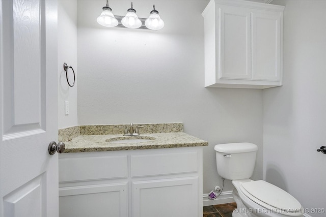 bathroom featuring baseboards, vanity, and toilet