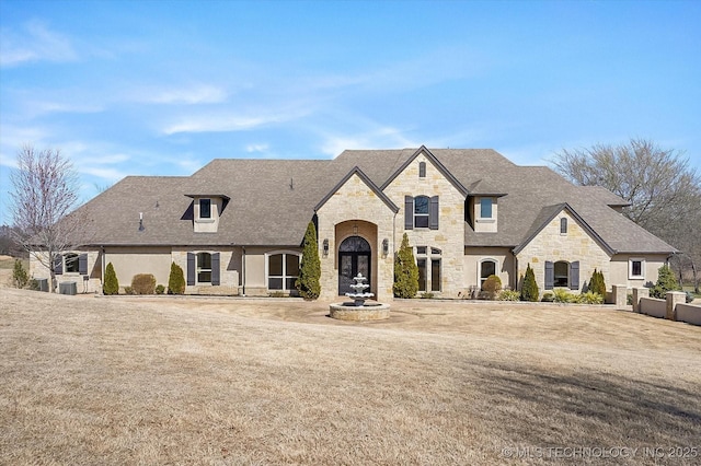 french provincial home featuring stone siding and a shingled roof