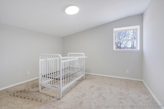 unfurnished bedroom featuring light colored carpet, vaulted ceiling, a crib, and baseboards