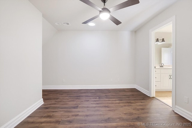 empty room featuring dark wood-type flooring, a sink, and baseboards