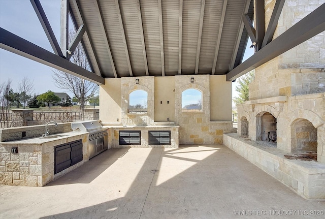 view of patio / terrace with an outdoor stone fireplace, a sink, grilling area, and area for grilling