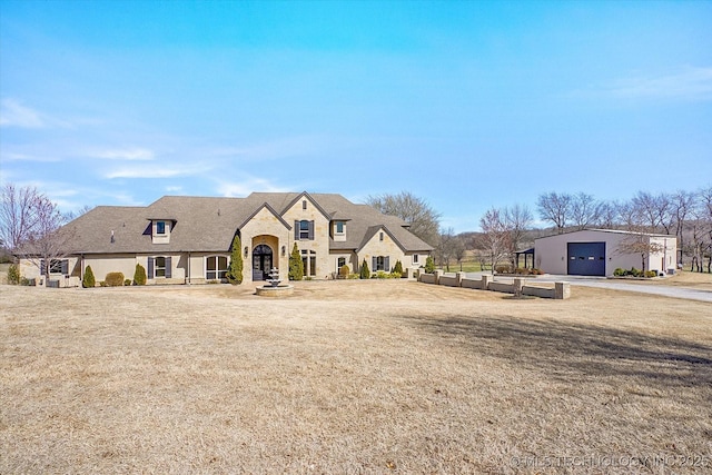 french country home with a front yard and a detached garage