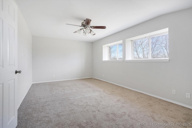 carpeted empty room with ceiling fan and baseboards