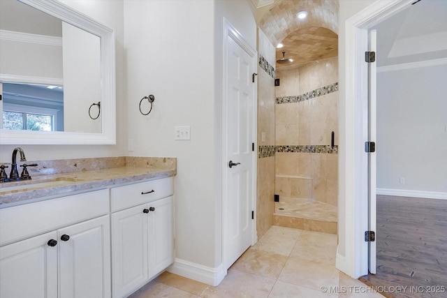 bathroom with a stall shower, crown molding, vanity, and baseboards