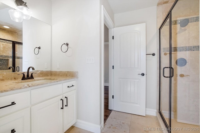 full bath featuring a stall shower, tile patterned flooring, baseboards, and vanity