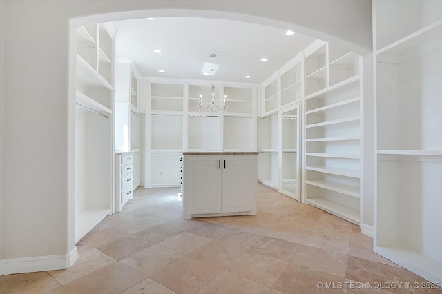 spacious closet with arched walkways and a notable chandelier