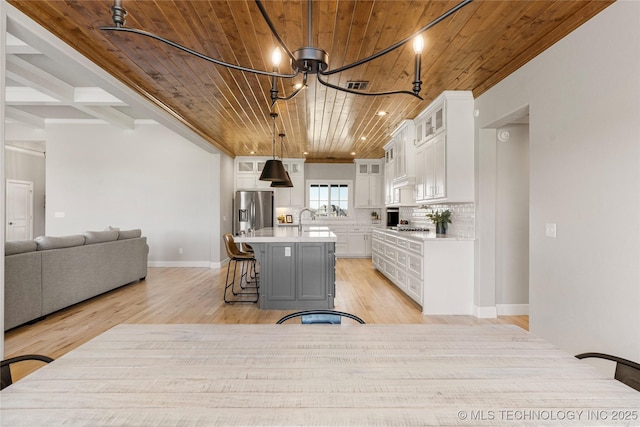 kitchen with light countertops, glass insert cabinets, open floor plan, white cabinetry, and a kitchen island