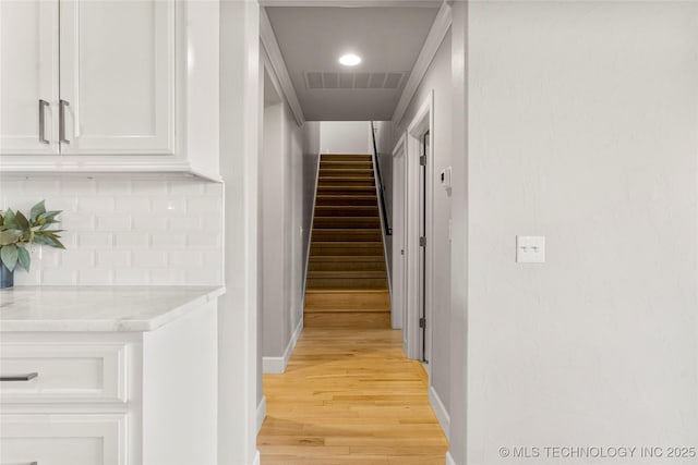 corridor with light wood finished floors, baseboards, stairs, and visible vents