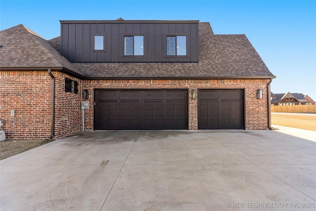 view of front of house with a shingled roof, concrete driveway, brick siding, and board and batten siding