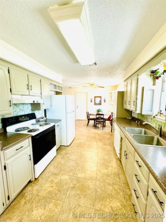 kitchen with ceiling fan, under cabinet range hood, white appliances, a sink, and dark countertops