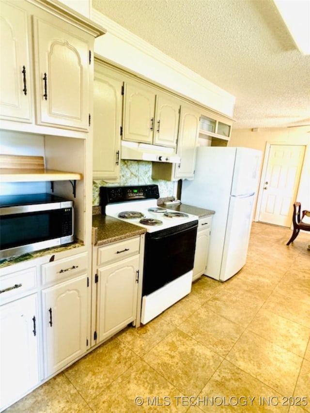 kitchen featuring under cabinet range hood, range with electric stovetop, freestanding refrigerator, stainless steel microwave, and dark countertops