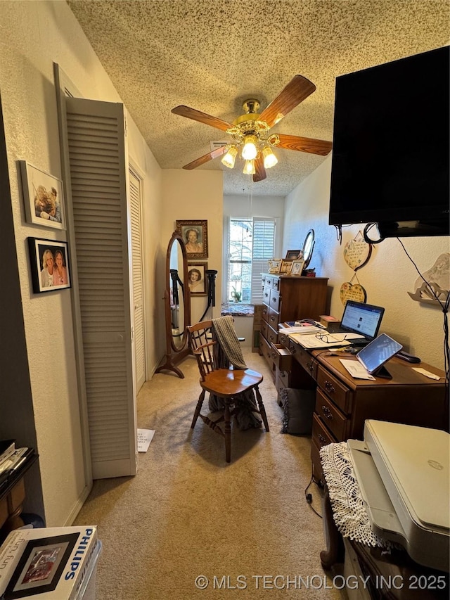 office space featuring a textured wall, light colored carpet, ceiling fan, and a textured ceiling