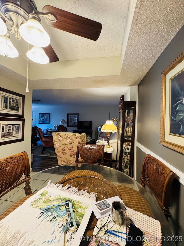 tiled dining space with a ceiling fan and a textured ceiling