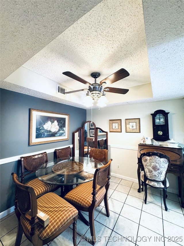 dining area with a textured ceiling, baseboards, visible vents, ceiling fan, and light tile patterned floors