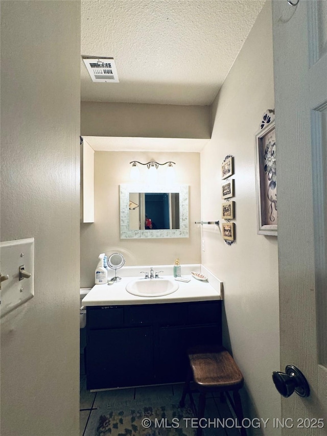 bathroom featuring vanity, tile patterned floors, visible vents, and a textured ceiling
