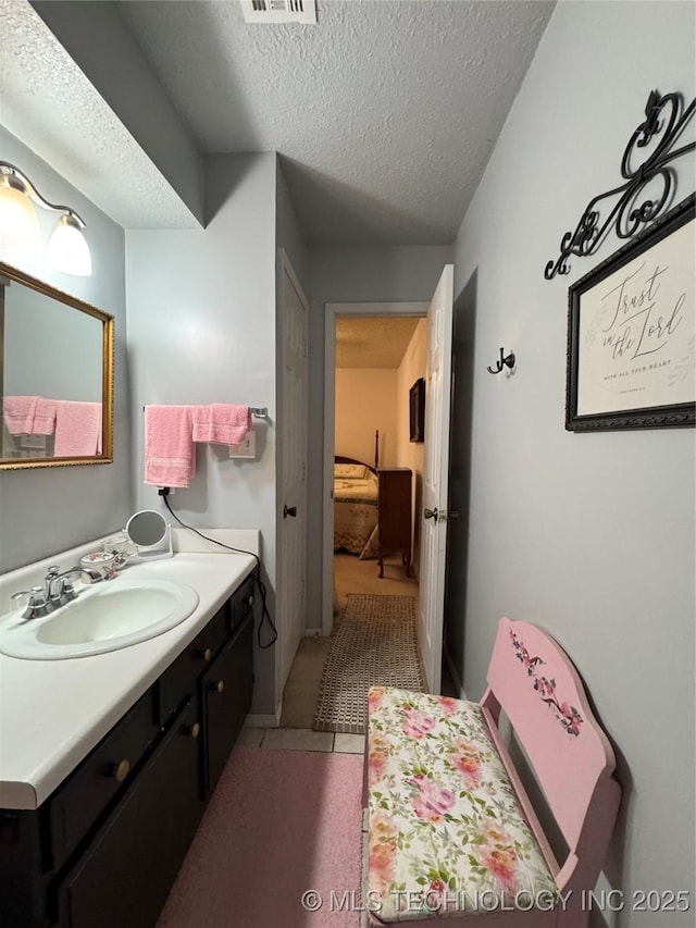 bathroom with tile patterned flooring, vanity, a textured ceiling, and visible vents