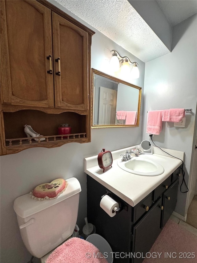 bathroom featuring a textured ceiling, toilet, and vanity