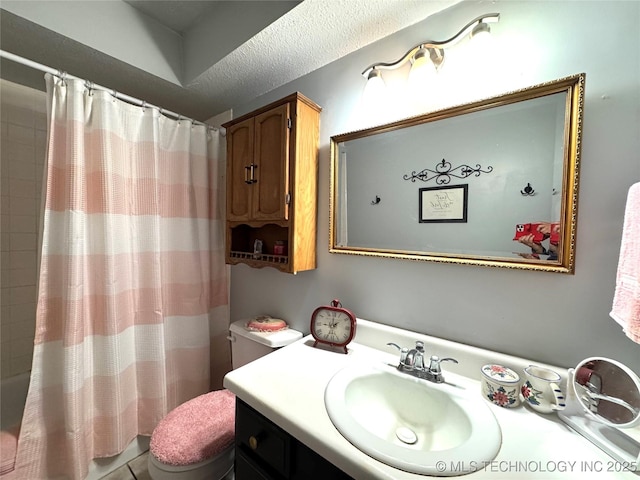 bathroom featuring shower / tub combo, toilet, vanity, and a textured ceiling
