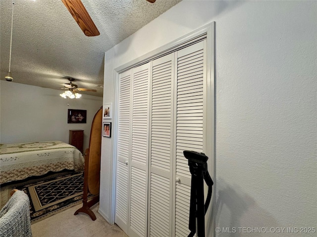 bedroom featuring a ceiling fan, a textured ceiling, a closet, and light colored carpet