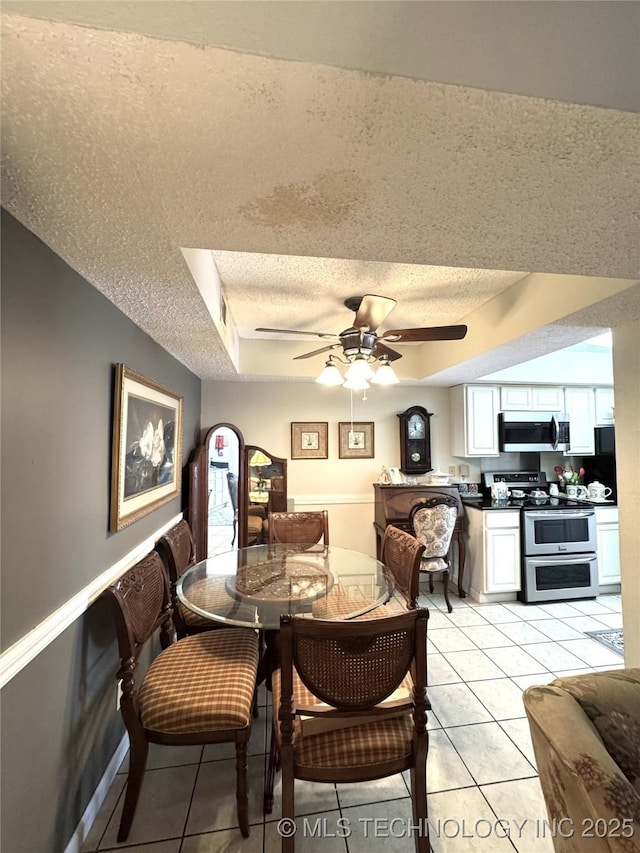 dining room featuring a textured ceiling, ceiling fan, and light tile patterned floors