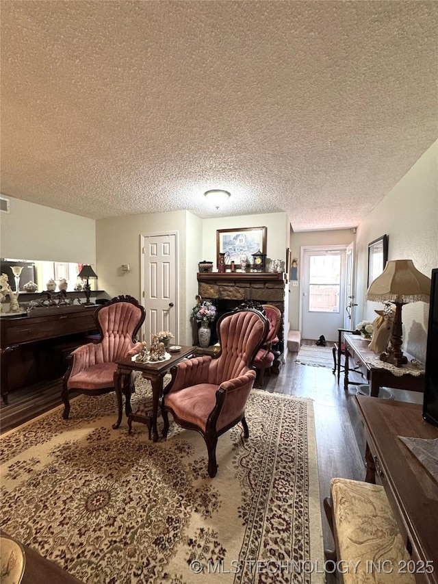6371 S 80th E Ave Unit 6H, Tulsa, OK 74133 - living room with wood finished floors, a stone fireplace, and a textured ceiling
