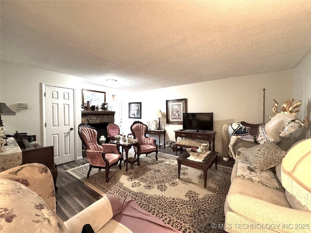 living area featuring a fireplace, wood finished floors, and a textured ceiling