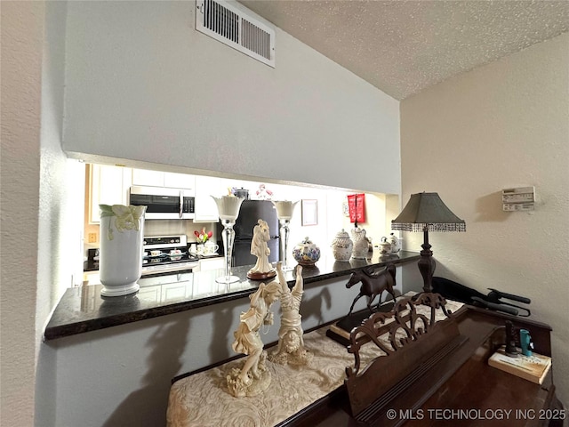 interior space with lofted ceiling, a textured wall, and visible vents