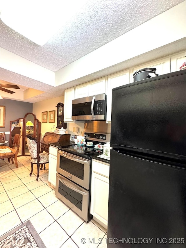 kitchen featuring a textured ceiling, light tile patterned flooring, white cabinetry, a ceiling fan, and appliances with stainless steel finishes