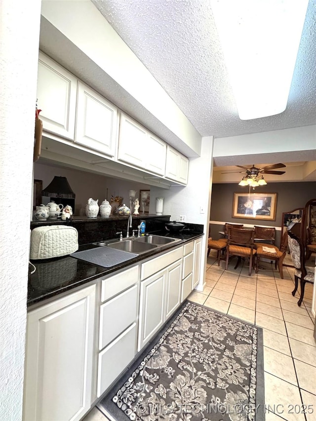 6371 S 80th E Ave Unit 6H, Tulsa, OK 74133 - kitchen with white cabinetry, dark countertops, light tile patterned floors, a textured ceiling, and a ceiling fan