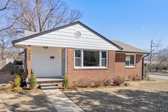 bungalow-style home with covered porch, brick siding, and central air condition unit