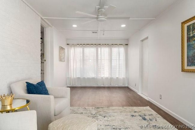 sitting room featuring ceiling fan, recessed lighting, brick wall, wood finished floors, and baseboards