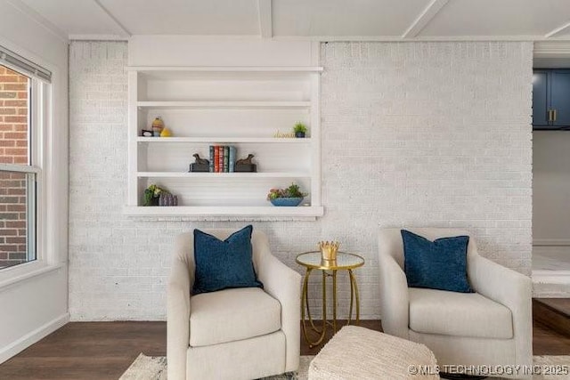 living area featuring brick wall and wood finished floors