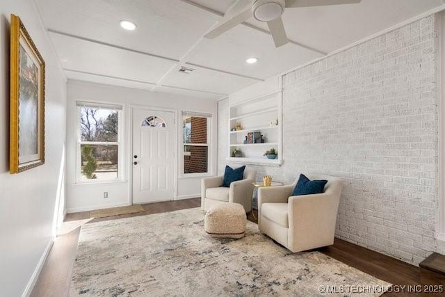 sitting room with built in features, recessed lighting, brick wall, wood finished floors, and baseboards