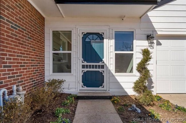 doorway to property with brick siding and an attached garage