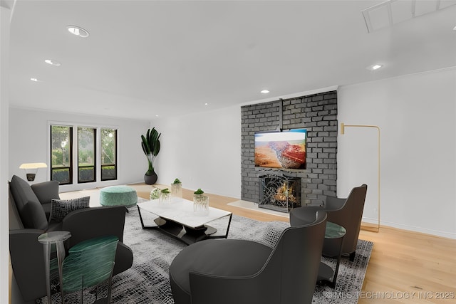 living room with a brick fireplace, light wood-style flooring, baseboards, and recessed lighting