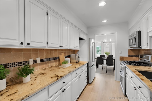 kitchen with light wood-type flooring, appliances with stainless steel finishes, white cabinets, and crown molding