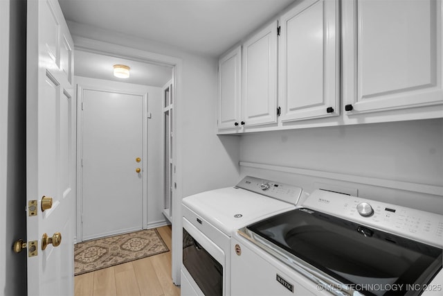 laundry room with light wood-type flooring, washing machine and clothes dryer, and cabinet space