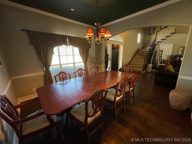 dining room with arched walkways, ornamental molding, dark wood-type flooring, an inviting chandelier, and stairs