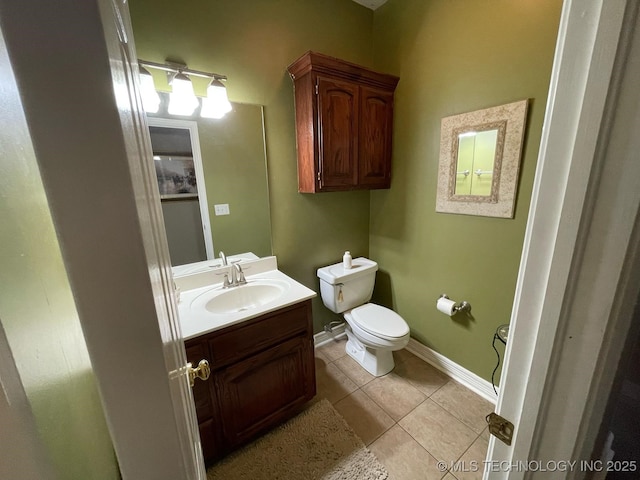 half bath featuring toilet, tile patterned flooring, vanity, and baseboards