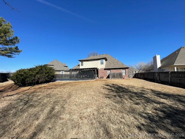 back of property featuring brick siding, fence, and a pergola