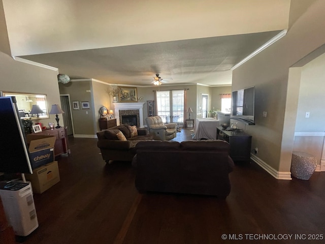 living room featuring dark wood-style floors, a fireplace, ornamental molding, ceiling fan, and baseboards