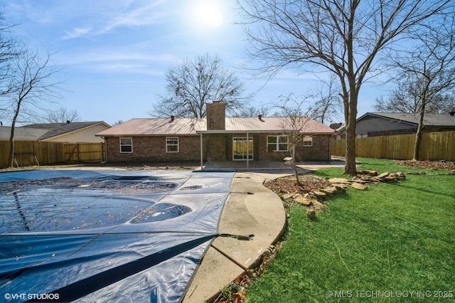 back of house featuring a patio, a lawn, a chimney, and a fenced backyard