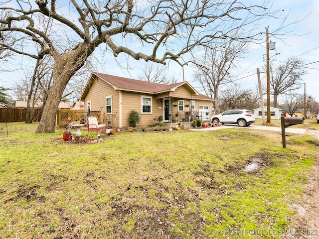 ranch-style house featuring an attached garage, fence, and a front lawn