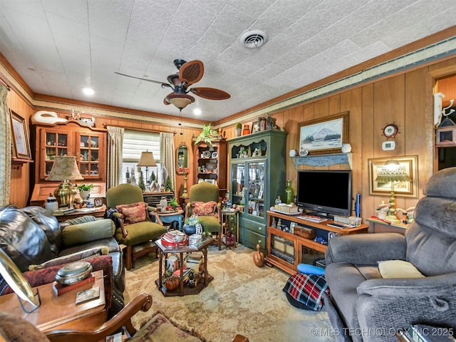 living area with ceiling fan, visible vents, and wooden walls