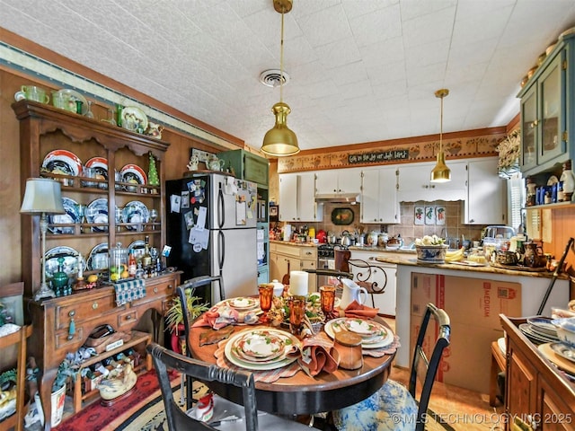 kitchen featuring decorative light fixtures, visible vents, white cabinetry, appliances with stainless steel finishes, and glass insert cabinets