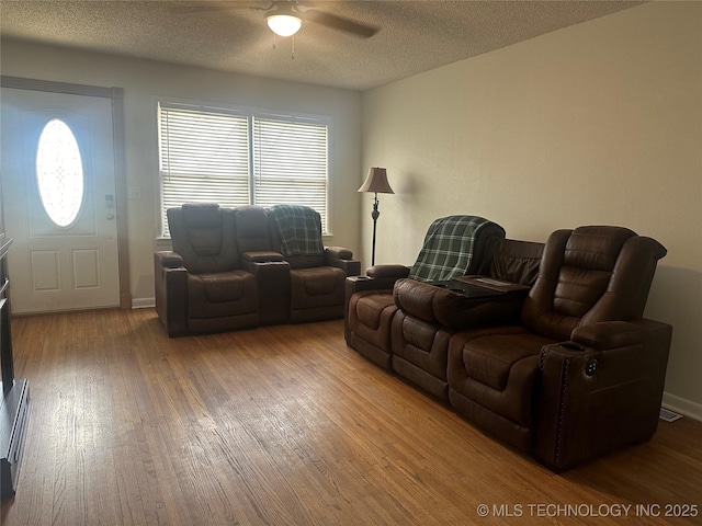 living area featuring baseboards, a textured ceiling, a ceiling fan, and hardwood / wood-style floors