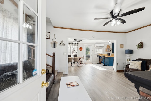 living area featuring a ceiling fan, baseboards, ornamental molding, and wood finished floors