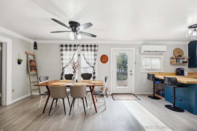 dining space with light wood-style floors, a wall unit AC, baseboards, and a ceiling fan