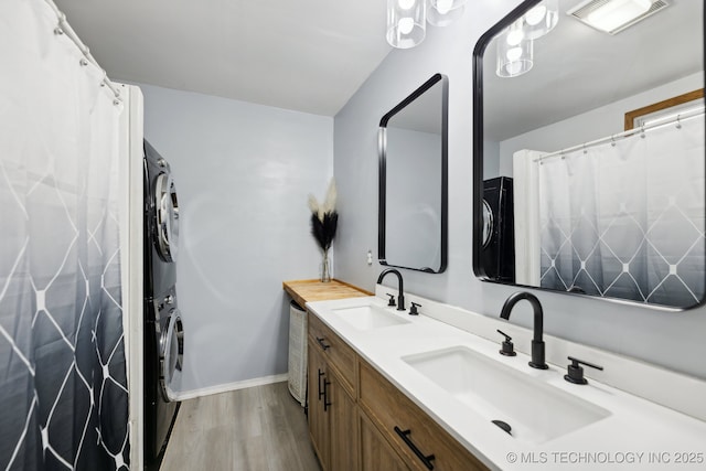 full bath with visible vents, double vanity, a sink, and stacked washer and clothes dryer